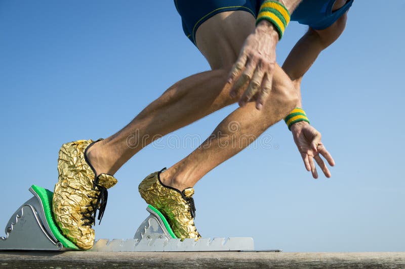 Idrottsman nen med guld- rinnande skor som startar ett lopp arkivfoto Idrottsman nen med guld- rinnande skor som startar ett lopp arkivfoto