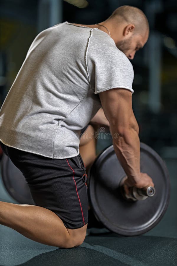 Idrottsutövare som lägger till viktplattor på sin barbell royaltyfri fotografi