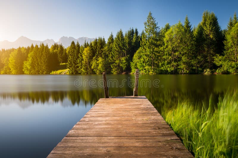 Idyllische Ansicht des hölzernen Piers im See mit Gebirgslandschaftshintergrund stockfotos