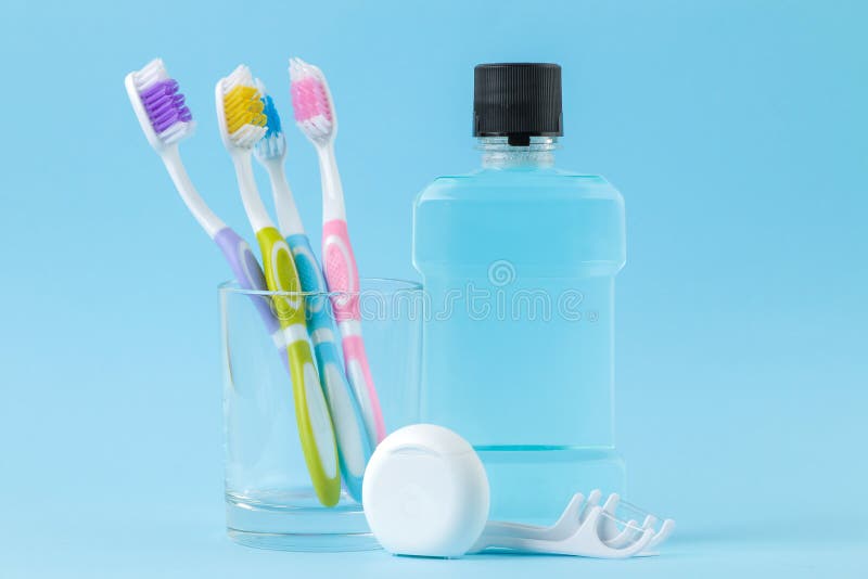 Igiene orale Spazzolino da denti, filo per i denti e risciacquo per la bocca e denti su un fondo blu delicato