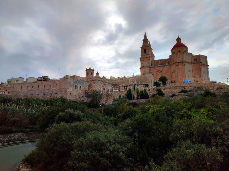 Following up Triq il-Marfa (Marfa Road), the view leads to the Parish Church and Sanctuary Of Our Lady, dominating the city silhouette of Mellieha, Malta. December 3, 2023. Following up Triq il-Marfa (Marfa Road), the view leads to the Parish Church and Sanctuary Of Our Lady, dominating the city silhouette of Mellieha, Malta. December 3, 2023