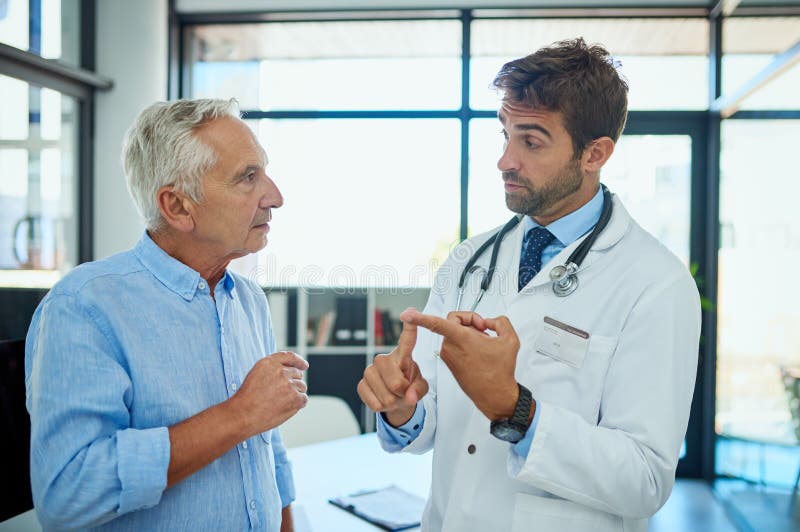Ihn durch die Schritte der Genesung zu führen. einen Arzt, der einen männlichen leitenden Patienten in seinem Büro berät. lizenzfreie stockbilder