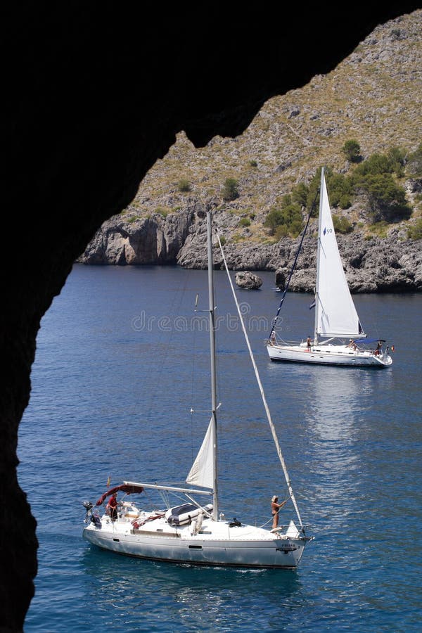 A view of two anchoring sailboats through a window in a cave. A view of two anchoring sailboats through a window in a cave...