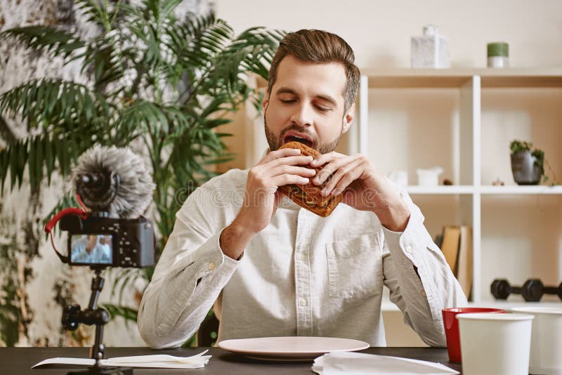 Ik houd van voedsel! Portret van opgewekt voedsel dat blogger een sandwich eet terwijl online het stromen in sociale media stock afbeeldingen Ik houd van voedsel! Portret van opgewekt voedsel dat blogger een sandwich eet terwijl online het stromen in sociale media stock afbeeldingen