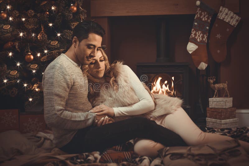 Il amore si accoppia dal fuoco di ceppo al Natale fotografie stock libere da diritti Il amore si accoppia dal fuoco di ceppo al Natale fotografie stock libere da diritti