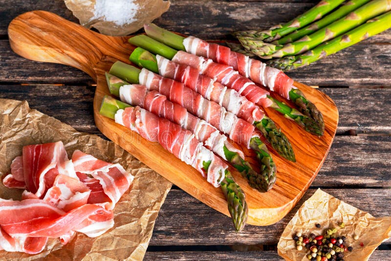 Il bacon crudo organico fresco ha avvolto l'asparago sulla tavola di legno fotografie stock libere da diritti Il bacon crudo organico fresco ha avvolto l'asparago sulla tavola di legno fotografie stock libere da diritti