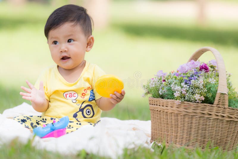Il bambino asiatico sorridente del ragazzo si siede su cotone bianco nei gras verdi immagini stock libere da diritti Il bambino asiatico sorridente del ragazzo si siede su cotone bianco nei gras verdi immagini stock libere da diritti