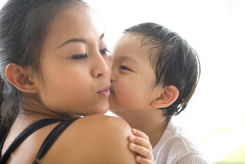 Il bambino bacia la sua mamma sulla sua guancica