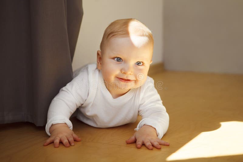 Il bambino con i grandi occhi in cingoli si trova sul pavimento di legno fotografia stock libera da diritti Il bambino con i grandi occhi in cingoli si trova sul pavimento di legno fotografia stock libera da diritti