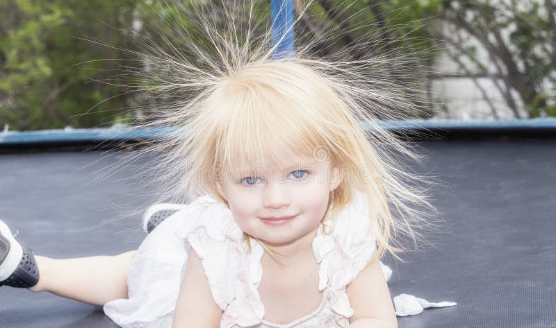 Il bambino della bambina gioca su un trampolino ed ha elettricità statica in suoi capelli fotografie stock