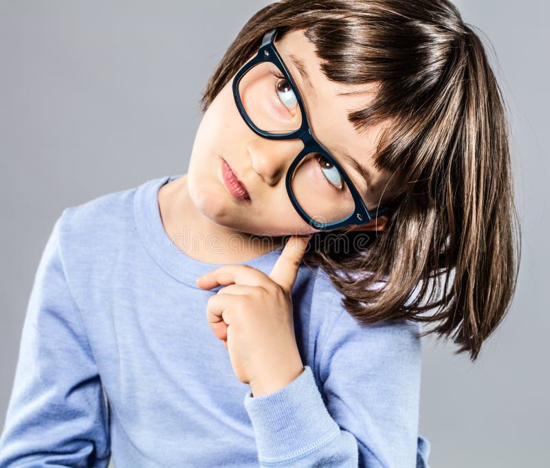 Il bambino piccolo astuto con la tenuta seria degli occhiali si dirige verso l'intelligenza immagini stock libere da diritti Il bambino piccolo astuto con la tenuta seria degli occhiali si dirige verso l'intelligenza immagini stock libere da diritti