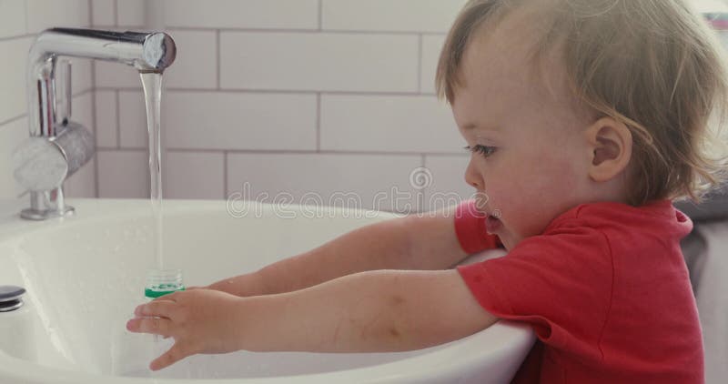 Il bambino riempie una bottiglia di acqua di plastica con acqua di rubinetto