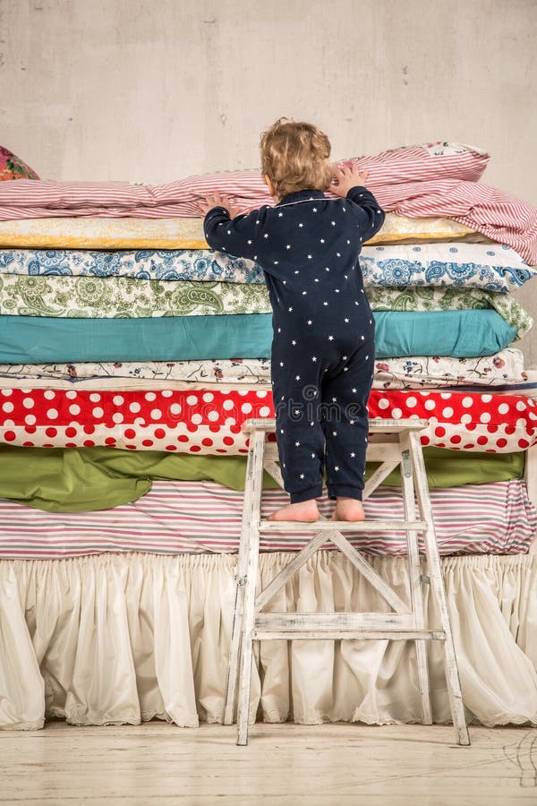 Child climbs on the bed with lots of quilts - Princess and the Pea. Child climbs on the bed with lots of quilts - Princess and the Pea.