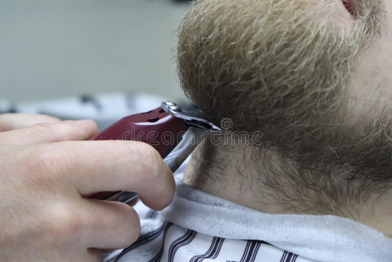Il barbiere rade la barba dell'uomo del cliente sul parrucchiere della sedia Taglio di capelli della barba barbiere che rade barb fotografia stock libera da diritti Il barbiere rade la barba dell'uomo del cliente sul parrucchiere della sedia Taglio di capelli della barba barbiere che rade barb fotografia stock libera da diritti