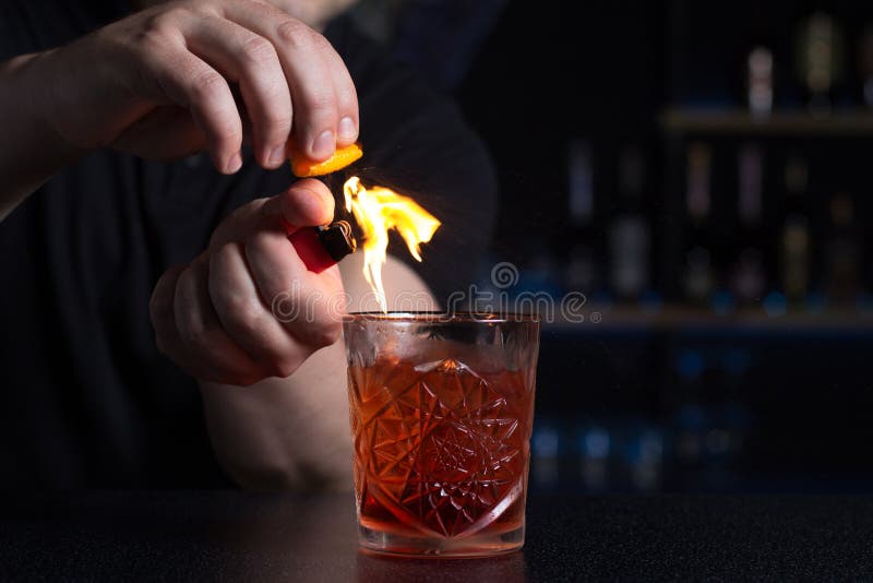 Il barista fa la fiamma sopra un cocktail con scorza d'arancia fotografie stock Il barista fa la fiamma sopra un cocktail con scorza d'arancia fotografie stock