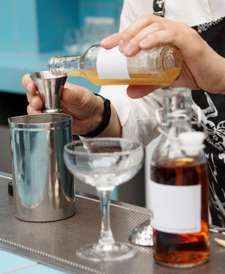 Il barista sta versando l'infusione in un vetro mescolantesi immagine stock libera da diritti Il barista sta versando l'infusione in un vetro mescolantesi immagine stock libera da diritti