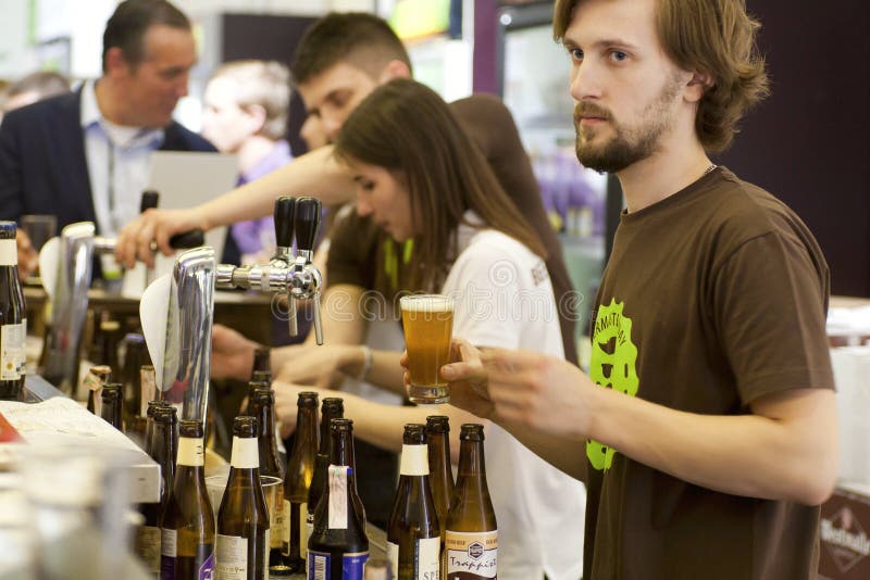 Il barista versa la birra del rubinetto del mestiere in pub occupato immagini stock libere da diritti Il barista versa la birra del rubinetto del mestiere in pub occupato immagini stock libere da diritti