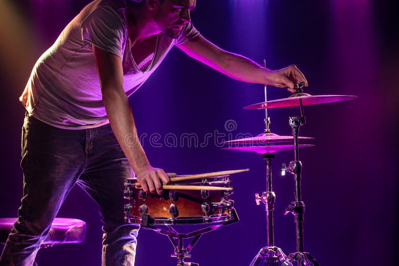 The drummer plays the drums. Beautiful blue and red background, with rays of light. Beautiful special effects smoke and lighting. The process of playing a musical instrument. The concept of music. The drummer plays the drums. Beautiful blue and red background, with rays of light. Beautiful special effects smoke and lighting. The process of playing a musical instrument. The concept of music