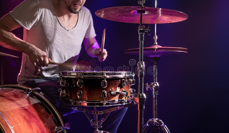 The drummer plays the drums. Beautiful blue and red background, with rays of light. Beautiful special effects smoke and lighting. The process of playing a musical instrument. The concept of music. The drummer plays the drums. Beautiful blue and red background, with rays of light. Beautiful special effects smoke and lighting. The process of playing a musical instrument. The concept of music