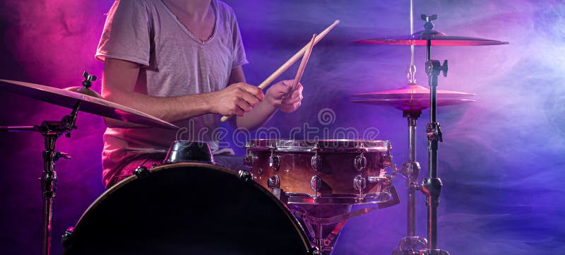 The drummer plays the drums. Beautiful blue and red background, with rays of light. Beautiful special effects smoke and lighting. The process of playing a musical instrument. The concept of music. The drummer plays the drums. Beautiful blue and red background, with rays of light. Beautiful special effects smoke and lighting. The process of playing a musical instrument. The concept of music