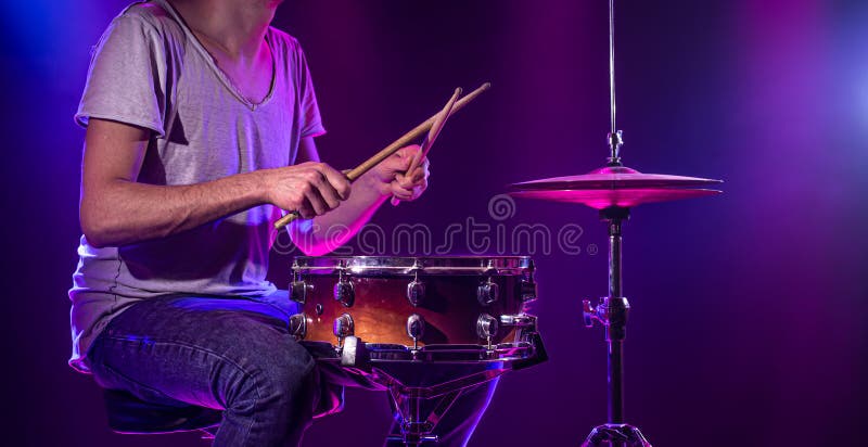 The drummer plays the drums. Beautiful blue and red background, with rays of light. Beautiful special effects smoke and lighting. The process of playing a musical instrument. The concept of music. The drummer plays the drums. Beautiful blue and red background, with rays of light. Beautiful special effects smoke and lighting. The process of playing a musical instrument. The concept of music