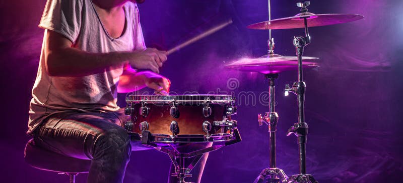 The drummer plays the drums. Beautiful blue and red background, with rays of light. Beautiful special effects smoke and lighting. The process of playing a musical instrument. The concept of music. The drummer plays the drums. Beautiful blue and red background, with rays of light. Beautiful special effects smoke and lighting. The process of playing a musical instrument. The concept of music