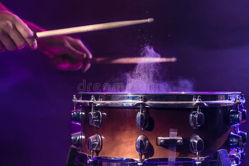 The drummer plays the drums. Beautiful blue and red background, with rays of light. Beautiful special effects smoke and lighting. The process of playing a musical instrument. The concept of music. The drummer plays the drums. Beautiful blue and red background, with rays of light. Beautiful special effects smoke and lighting. The process of playing a musical instrument. The concept of music