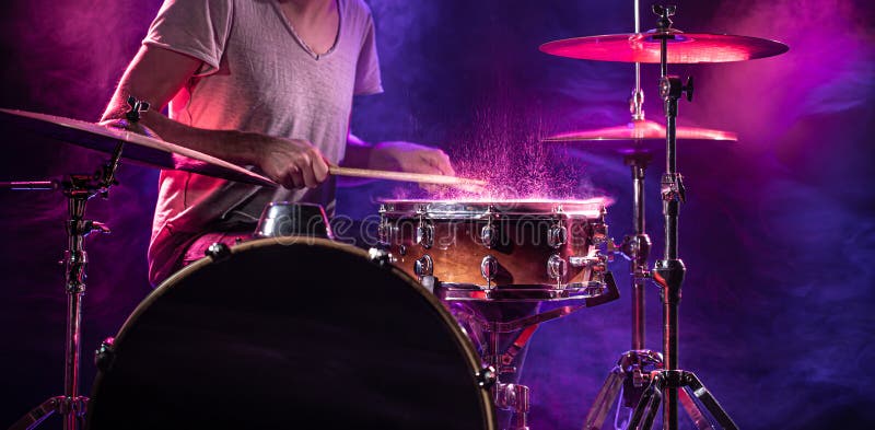 The drummer plays the drums. Beautiful blue and red background, with rays of light. Beautiful special effects smoke and lighting. The process of playing a musical instrument. The concept of music. The drummer plays the drums. Beautiful blue and red background, with rays of light. Beautiful special effects smoke and lighting. The process of playing a musical instrument. The concept of music