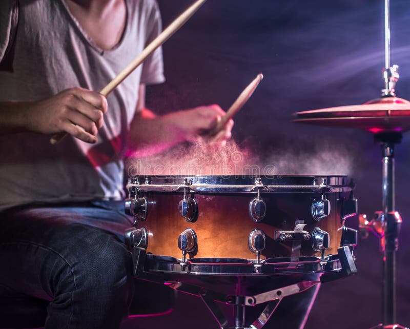 The drummer plays the drums. Beautiful blue and red background, with rays of light. Beautiful special effects smoke and lighting. The process of playing a musical instrument. The concept of music. The drummer plays the drums. Beautiful blue and red background, with rays of light. Beautiful special effects smoke and lighting. The process of playing a musical instrument. The concept of music