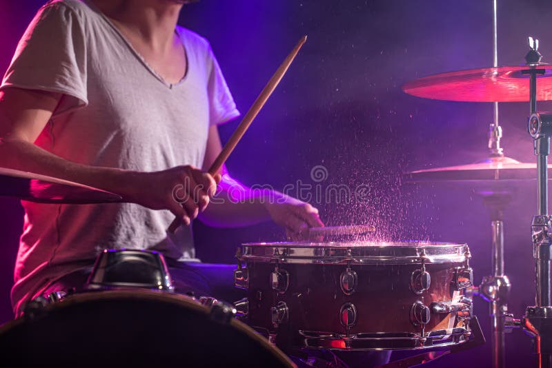 The drummer plays the drums. Beautiful blue and red background, with rays of light. Beautiful special effects smoke and lighting. The process of playing a musical instrument. The concept of music. The drummer plays the drums. Beautiful blue and red background, with rays of light. Beautiful special effects smoke and lighting. The process of playing a musical instrument. The concept of music