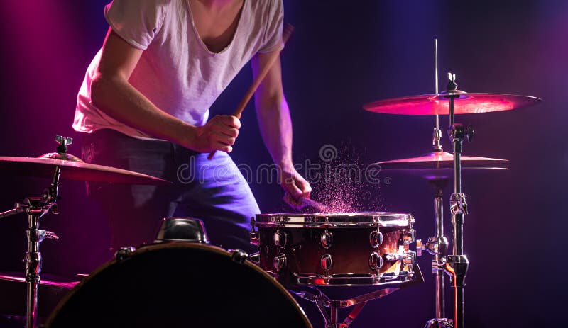 The drummer plays the drums. Beautiful blue and red background, with rays of light. Beautiful special effects smoke and lighting. The process of playing a musical instrument. The concept of music. The drummer plays the drums. Beautiful blue and red background, with rays of light. Beautiful special effects smoke and lighting. The process of playing a musical instrument. The concept of music