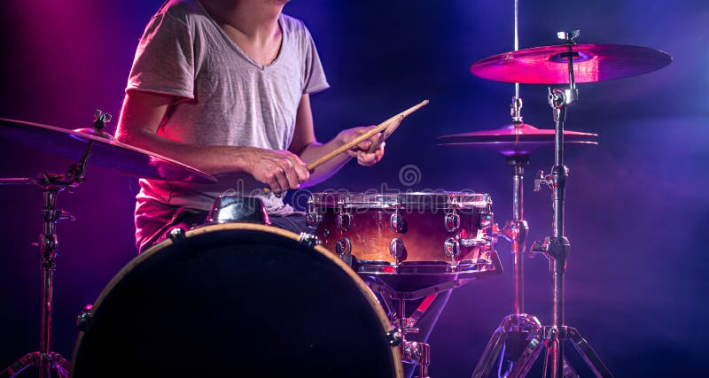 The drummer plays the drums. Beautiful blue and red background, with rays of light. Beautiful special effects smoke and lighting. The process of playing a musical instrument. The concept of music. The drummer plays the drums. Beautiful blue and red background, with rays of light. Beautiful special effects smoke and lighting. The process of playing a musical instrument. The concept of music