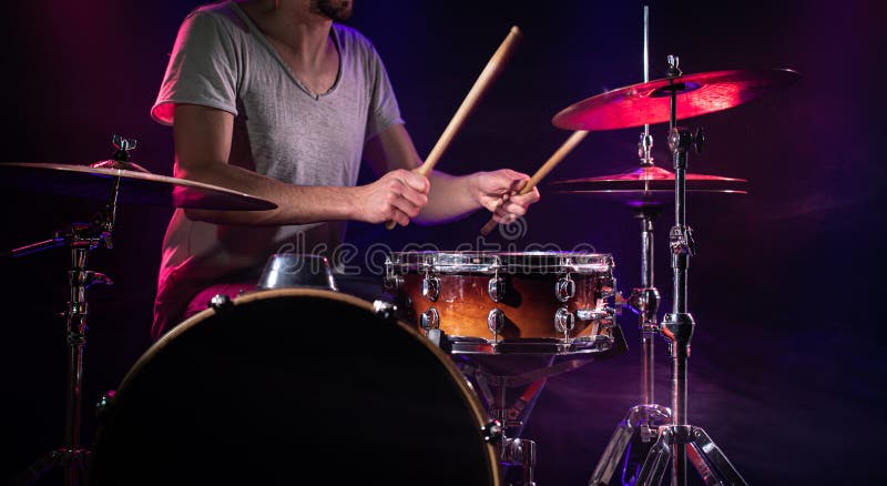 The drummer plays the drums. Beautiful blue and red background, with rays of light. Beautiful special effects smoke and lighting. The process of playing a musical instrument. The concept of music. The drummer plays the drums. Beautiful blue and red background, with rays of light. Beautiful special effects smoke and lighting. The process of playing a musical instrument. The concept of music