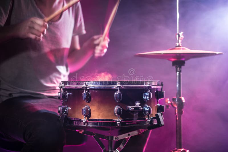 The drummer plays the drums. Beautiful blue and red background, with rays of light. Beautiful special effects smoke and lighting. The process of playing a musical instrument. The concept of music. The drummer plays the drums. Beautiful blue and red background, with rays of light. Beautiful special effects smoke and lighting. The process of playing a musical instrument. The concept of music