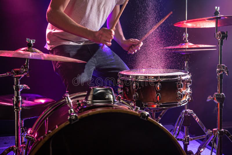 The drummer plays the drums. Beautiful blue and red background, with rays of light. Beautiful special effects smoke and lighting. The process of playing a musical instrument. The concept of music. The drummer plays the drums. Beautiful blue and red background, with rays of light. Beautiful special effects smoke and lighting. The process of playing a musical instrument. The concept of music