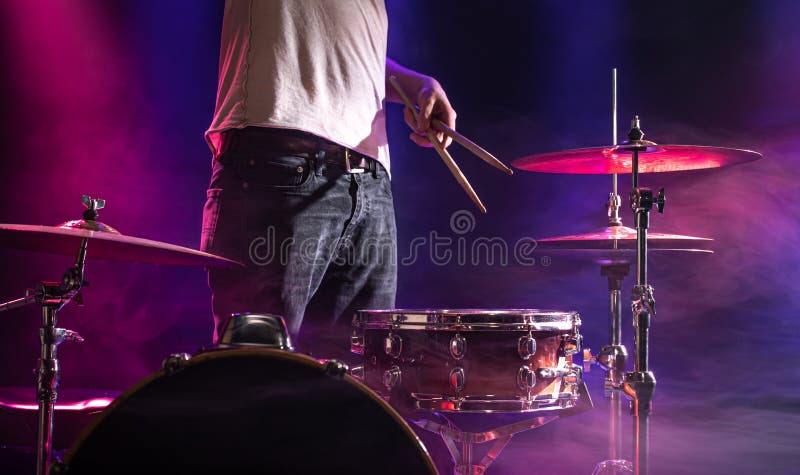 The drummer plays the drums. Beautiful blue and red background, with rays of light. Beautiful special effects smoke and lighting. The process of playing a musical instrument. The concept of music. The drummer plays the drums. Beautiful blue and red background, with rays of light. Beautiful special effects smoke and lighting. The process of playing a musical instrument. The concept of music