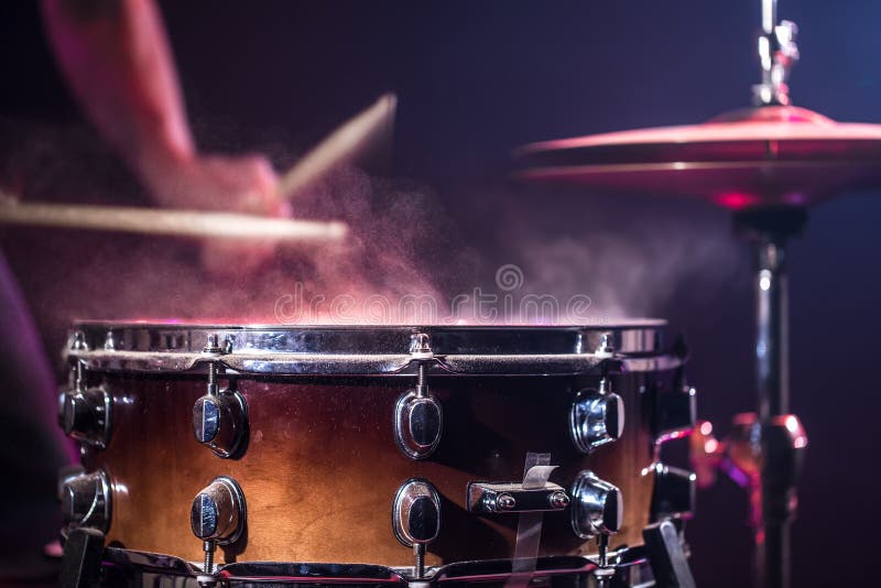 The drummer plays the drums. Beautiful blue and red background, with rays of light. Beautiful special effects smoke and lighting. The process of playing a musical instrument. The concept of music. The drummer plays the drums. Beautiful blue and red background, with rays of light. Beautiful special effects smoke and lighting. The process of playing a musical instrument. The concept of music