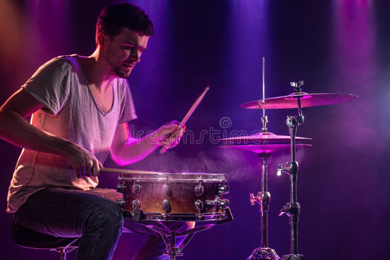 The drummer plays the drums. Beautiful blue and red background, with rays of light. Beautiful special effects smoke and lighting. The process of playing a musical instrument. The concept of music. The drummer plays the drums. Beautiful blue and red background, with rays of light. Beautiful special effects smoke and lighting. The process of playing a musical instrument. The concept of music