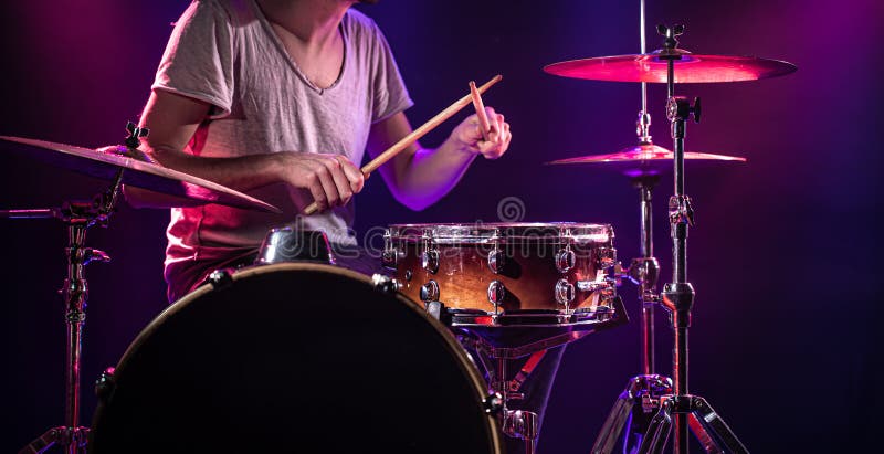 The drummer plays the drums. Beautiful blue and red background, with rays of light. Beautiful special effects smoke and lighting. The process of playing a musical instrument. The concept of music. The drummer plays the drums. Beautiful blue and red background, with rays of light. Beautiful special effects smoke and lighting. The process of playing a musical instrument. The concept of music