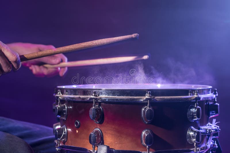 The drummer plays the drums. Beautiful blue and red background, with rays of light. Beautiful special effects smoke and lighting. The process of playing a musical instrument. The concept of music. The drummer plays the drums. Beautiful blue and red background, with rays of light. Beautiful special effects smoke and lighting. The process of playing a musical instrument. The concept of music