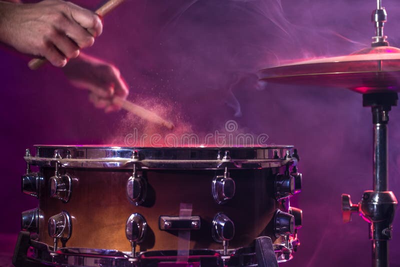 The drummer plays the drums. Beautiful blue and red background, with rays of light. Beautiful special effects smoke and lighting. The drummer plays the drums. Beautiful blue and red background, with rays of light. Beautiful special effects smoke and lighting