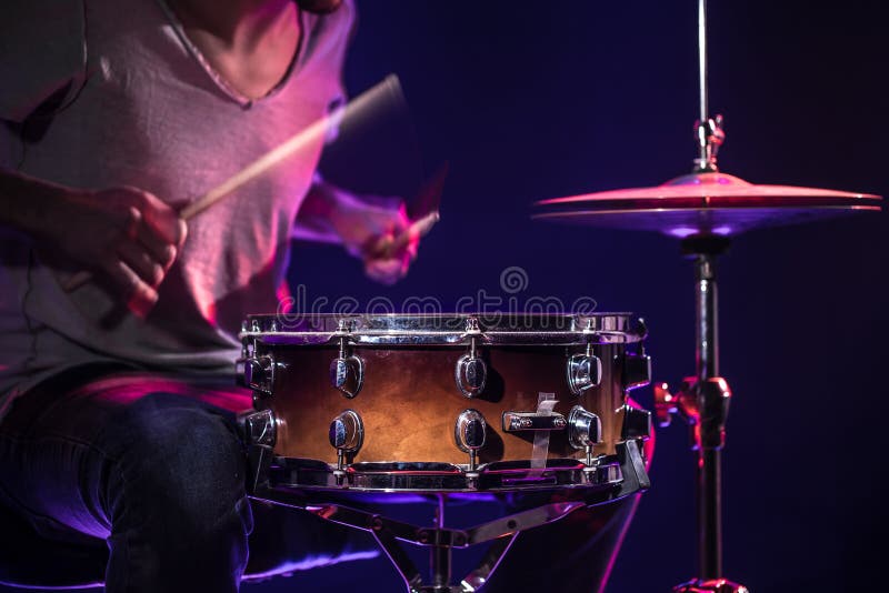 The drummer plays the drums. Beautiful blue and red background, with rays of light. Beautiful special effects smoke and lighting. The drummer plays the drums. Beautiful blue and red background, with rays of light. Beautiful special effects smoke and lighting