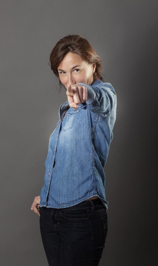 Il bello mezzo sicuro di sé ha invecchiato la donna che indica il suo dito in avanti fotografia stock Il bello mezzo sicuro di sé ha invecchiato la donna che indica il suo dito in avanti fotografia stock