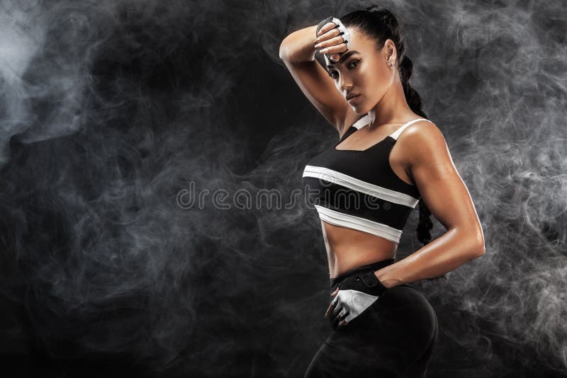 Il bello modello afroamericano sportivo, donna in sportwear fa la forma fisica che si esercita al fondo nero per restare adatto