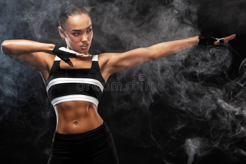 Il bello modello afroamericano sportivo, donna in sportwear fa la forma fisica che si esercita al fondo nero per restare adatto