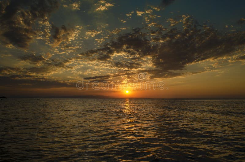 Il bello paesaggio ardente del tramonto in mare il mar Caspio ed il cielo arancio sopra con la riflessione dorata del sole impres fotografia stock Il bello paesaggio ardente del tramonto in mare il mar Caspio ed il cielo arancio sopra con la riflessione dorata del sole impres fotografia stock