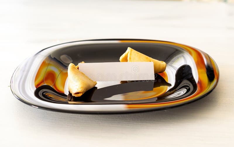 Il biscotto di fortuna si trova su una banda nera su un fondo leggero con una nota in bianco immagini stock libere da diritti Il biscotto di fortuna si trova su una banda nera su un fondo leggero con una nota in bianco immagini stock libere da diritti