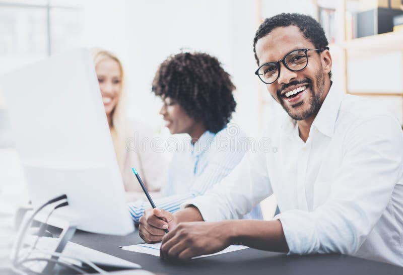 Il buio ha pelato i vetri d'uso dell'imprenditore, lavoranti nell'ufficio moderno Uomo afroamericano in camicia bianca che sorrid immagini stock Il buio ha pelato i vetri d'uso dell'imprenditore, lavoranti nell'ufficio moderno Uomo afroamericano in camicia bianca che sorrid immagini stock