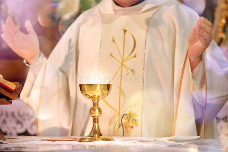 Il calice all'altare con i raggi di luce ed il sacerdote celebrano di massa
