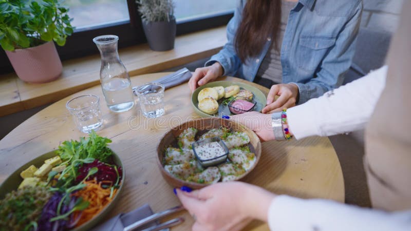 Il cameriere in un caffè accogliente ha portato un piatto vegetariano per un paio di visitatori. lo staff serve un uomo e una donn stock footage